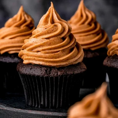 Cozy chocolate pumpkin cupcakes topped with creamy frosting and pumpkin spice sprinkles.