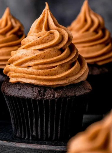 Cozy chocolate pumpkin cupcakes topped with creamy frosting and pumpkin spice sprinkles.