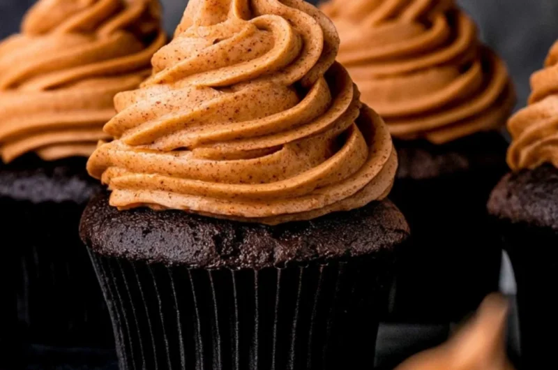 Cozy chocolate pumpkin cupcakes topped with creamy frosting and pumpkin spice sprinkles.