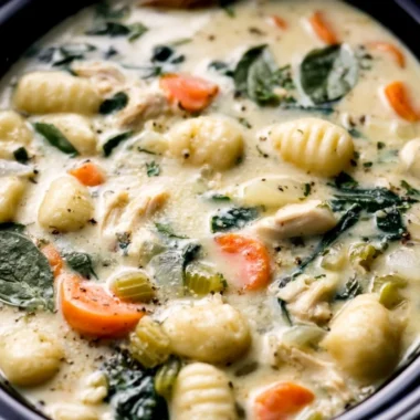 Bowl of Crockpot Chicken Gnocchi Soup with herbs and bread on the side
