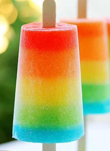 Colorful homemade rainbow popsicles stacked for a refreshing summer treat