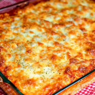 Delicious baked spaghetti topped with cheese and herbs in a rustic dish