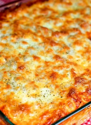 Delicious baked spaghetti topped with cheese and herbs in a rustic dish