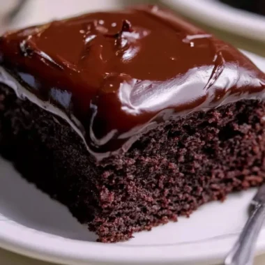 Wacky Chocolate Cake topped with colorful sprinkles and creamy chocolate frosting.