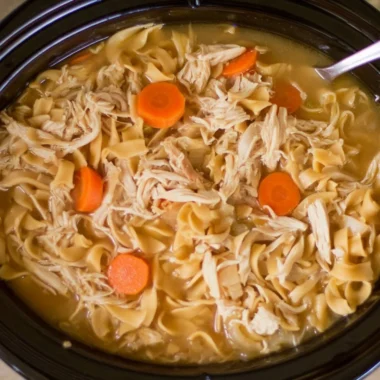 High protein chicken noodle soup in a bowl garnished with herbs and vegetables