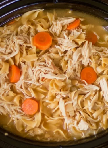 High protein chicken noodle soup in a bowl garnished with herbs and vegetables