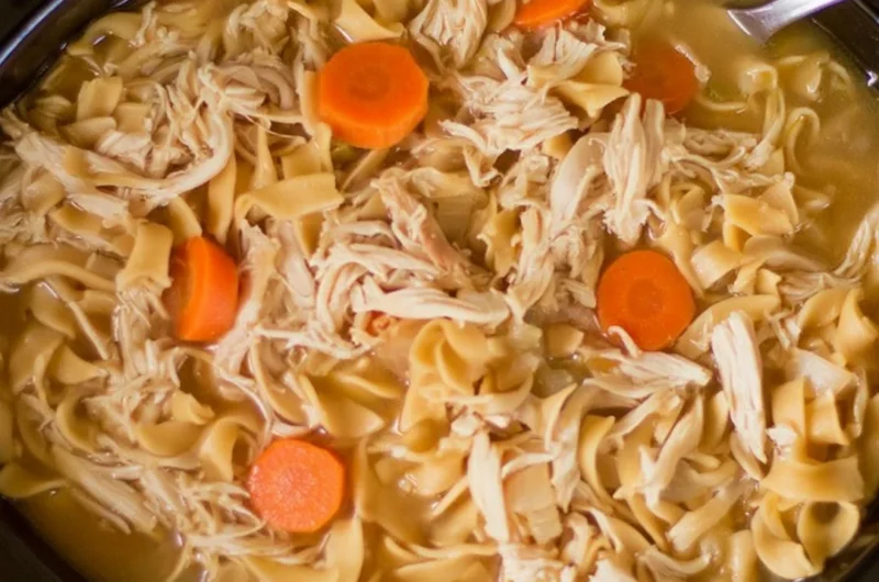 High protein chicken noodle soup in a bowl garnished with herbs and vegetables